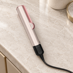 Closed pink air hair straightener on a neutral stone vanity with its power cable