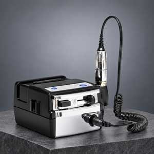 Electric nail drill with coiled handpiece cable displayed on a grey stone plinth