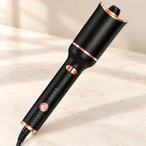 Black and rose-gold automatic hair curler displayed on a light ivory vanity surface