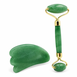 Green facial roller and gua sha on a white background