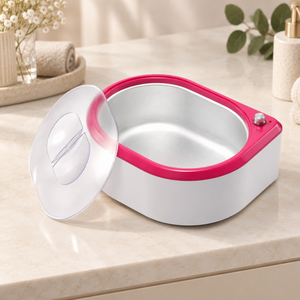 Pink and white paraffin wax bath styled on a neutral vanity with its clear lid resting beside it.