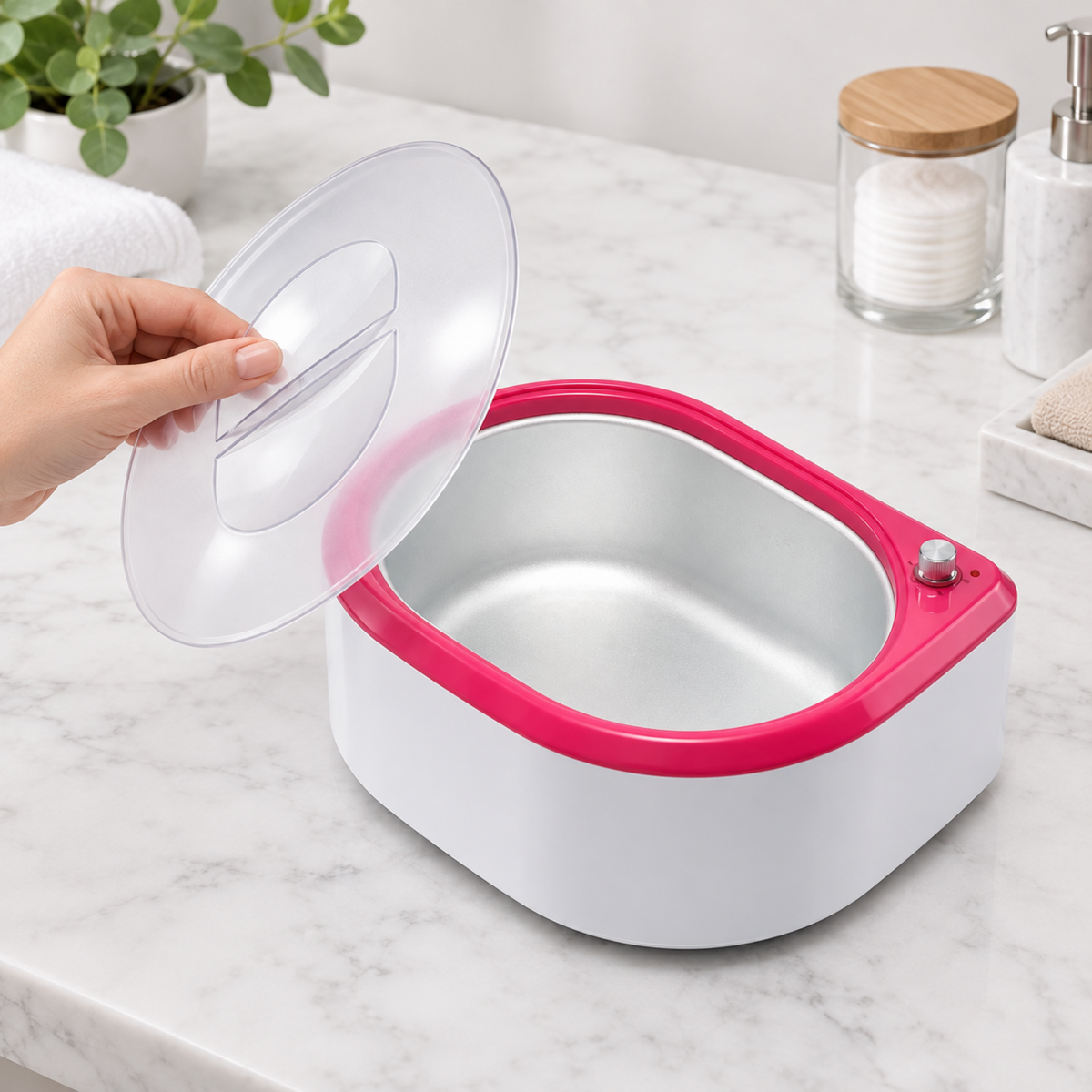 Hand lifting the clear lid from the pink and white paraffin wax bath on a beauty counter.