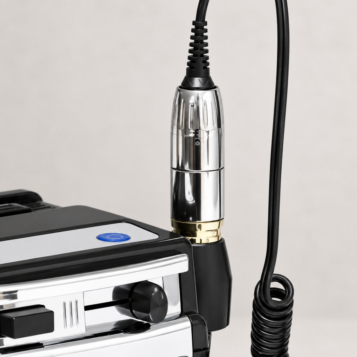 Chrome nail drill handpiece with gold-coloured collar in its side holder