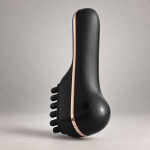 Black scalp massage comb showing its soft silicone head and metallic trim from a side angle.