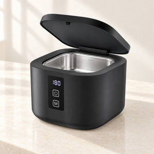 Black ultrasonic jewellery cleaner on a neutral dressing-table surface